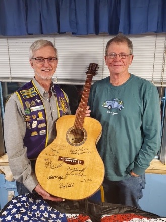 Everett Lions Club President Mark Rakoczy accepts a unique one of a kind guitar from Mike Snyder